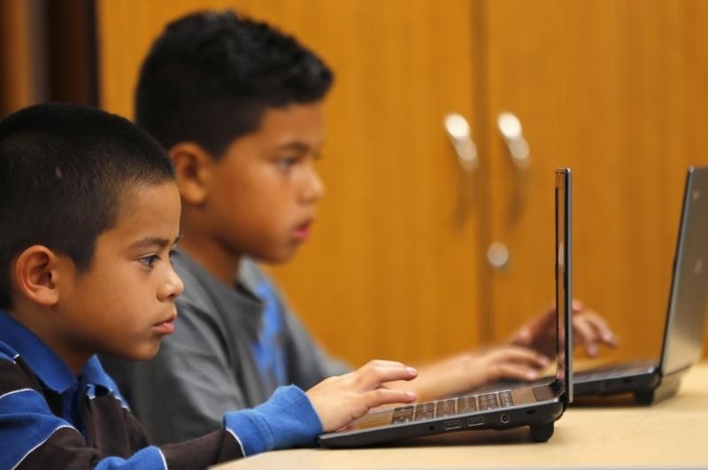 在加州圣地亚哥的君主学校，四年级的学生在笔记本电脑前工作
