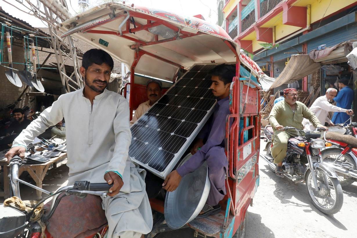酷暑期间，巴基斯坦雅各布阿巴德，人力车上的人们扛着太阳能电池板。