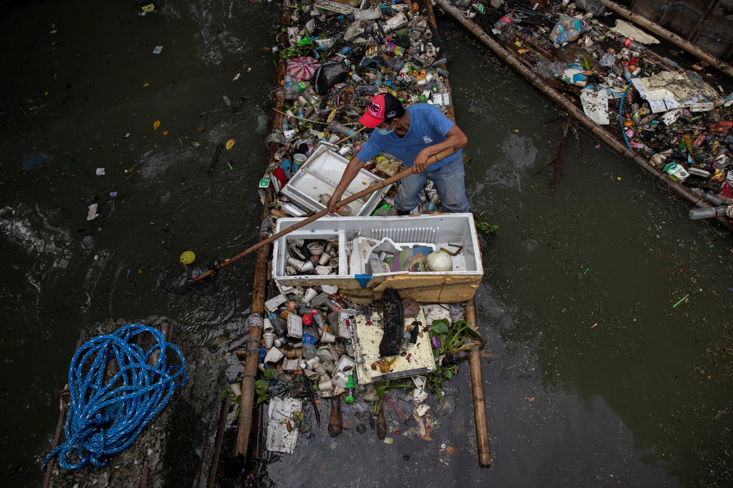 菲律宾曼达卢永市，一名男子在严重污染的圣胡安河收集垃圾，圣胡安河是帕西格河的一条支流。